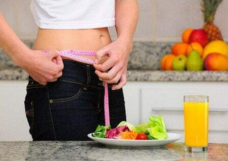 A girl on a diet measures her waist size